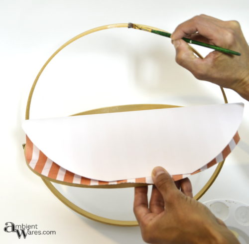 Spreading glue on embroidery hoop edges to adhere scrapbook paper