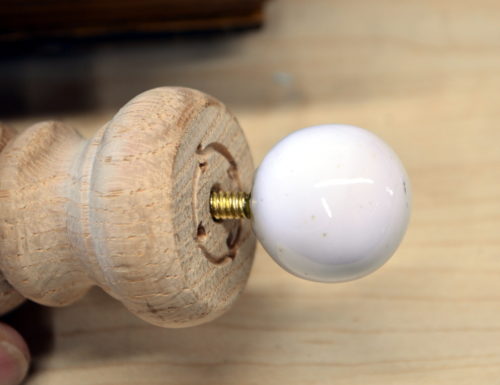 Wooden finial being fitted with another glass top finial